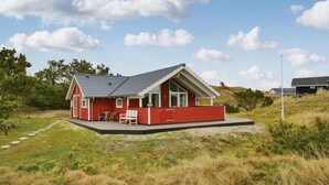 A red house with a sloped roof, a small porch with two chairs, and a path of stepping stones leading to the entrance. - Amazing home in Fanø with WiFi (Fanø)