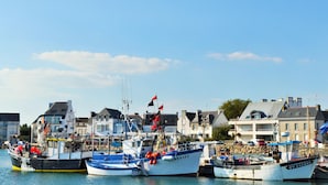 Ein Hafen mit mehreren vertäuten Booten, umgeben von Gebäuden mit unterschiedlicher Architektur.