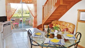 Ein Essbereich mit einem Glastisch, gedeckt für vier Personen, einer Holztreppe und Blick auf einen Garten durch eine Glastür.