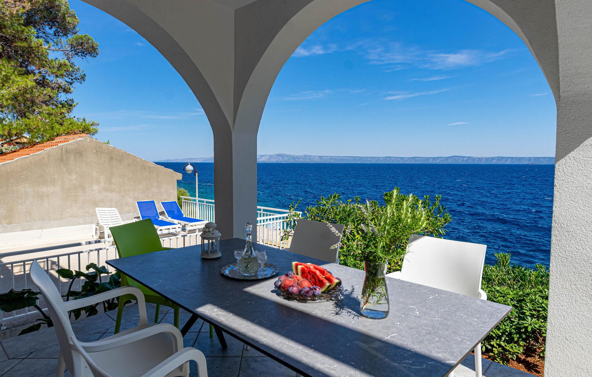 Terraço com mesa posta para refeições, com vista para o mar.