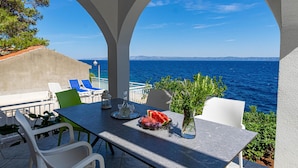 Una terraza con mesa lista para comer, con vista al mar.