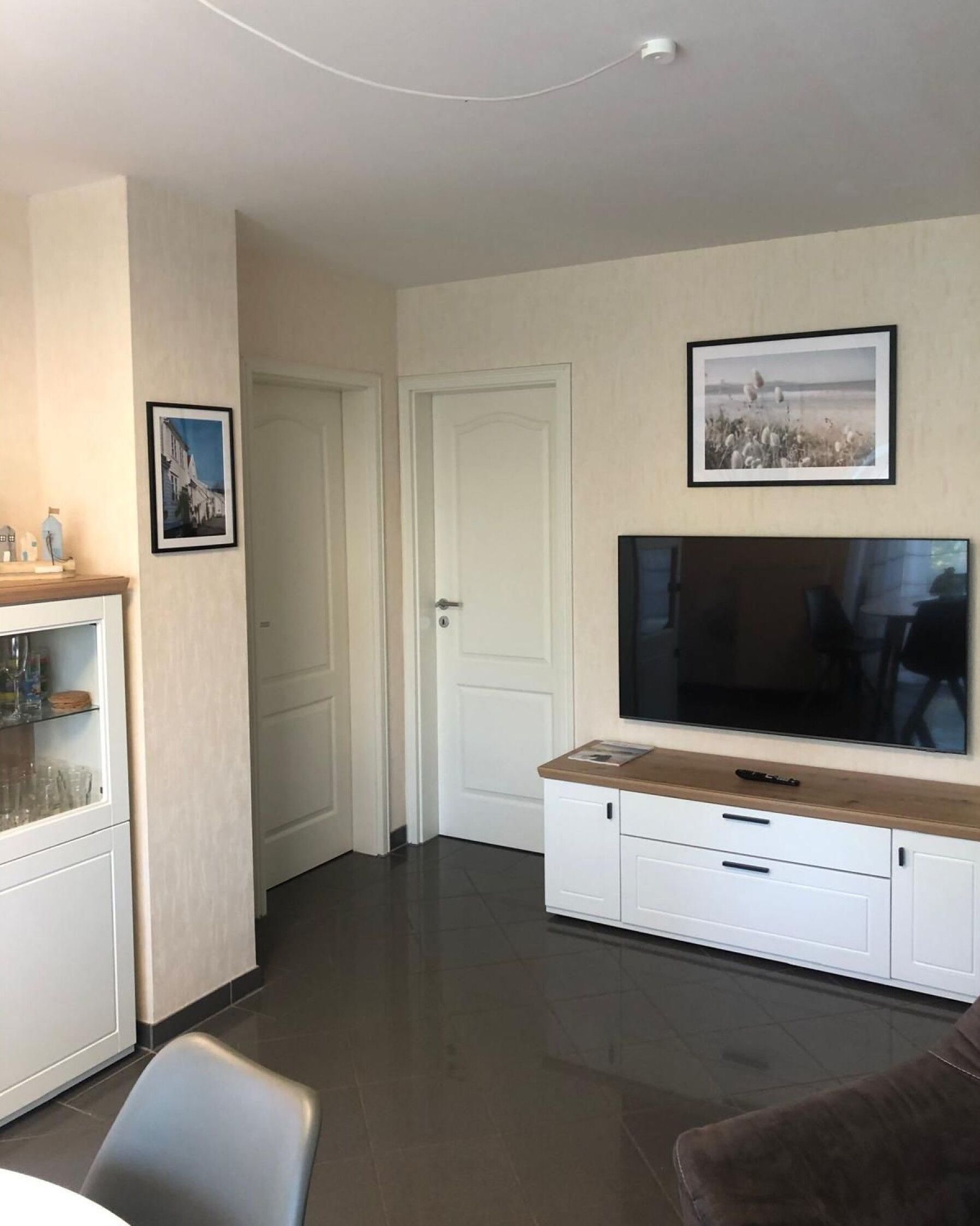 Un salon moderne doté d’un téléviseur à écran plat, d’un meuble en bois et d’une porte donnant sur une autre pièce.