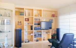 Relax in this stylish living room with a flat-screen TV, sound system, and comfortable seating.