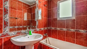 A bathroom with red tiles, a white sink, a mirror, and a bathtub. - Amazing home in Orihuela Costa (Orihuela Costa)