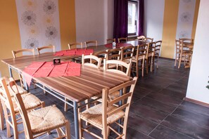 A dining area with a long wooden table, multiple chairs, and a red placemat.
