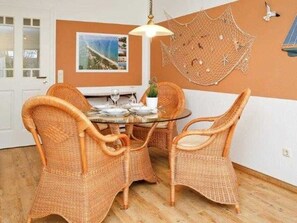 A dining area with wicker chairs, a glass table, and a hanging net decoration.