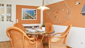 Un comedor con sillas de mimbre, una mesa de vidrio y una decoración de red colgante.