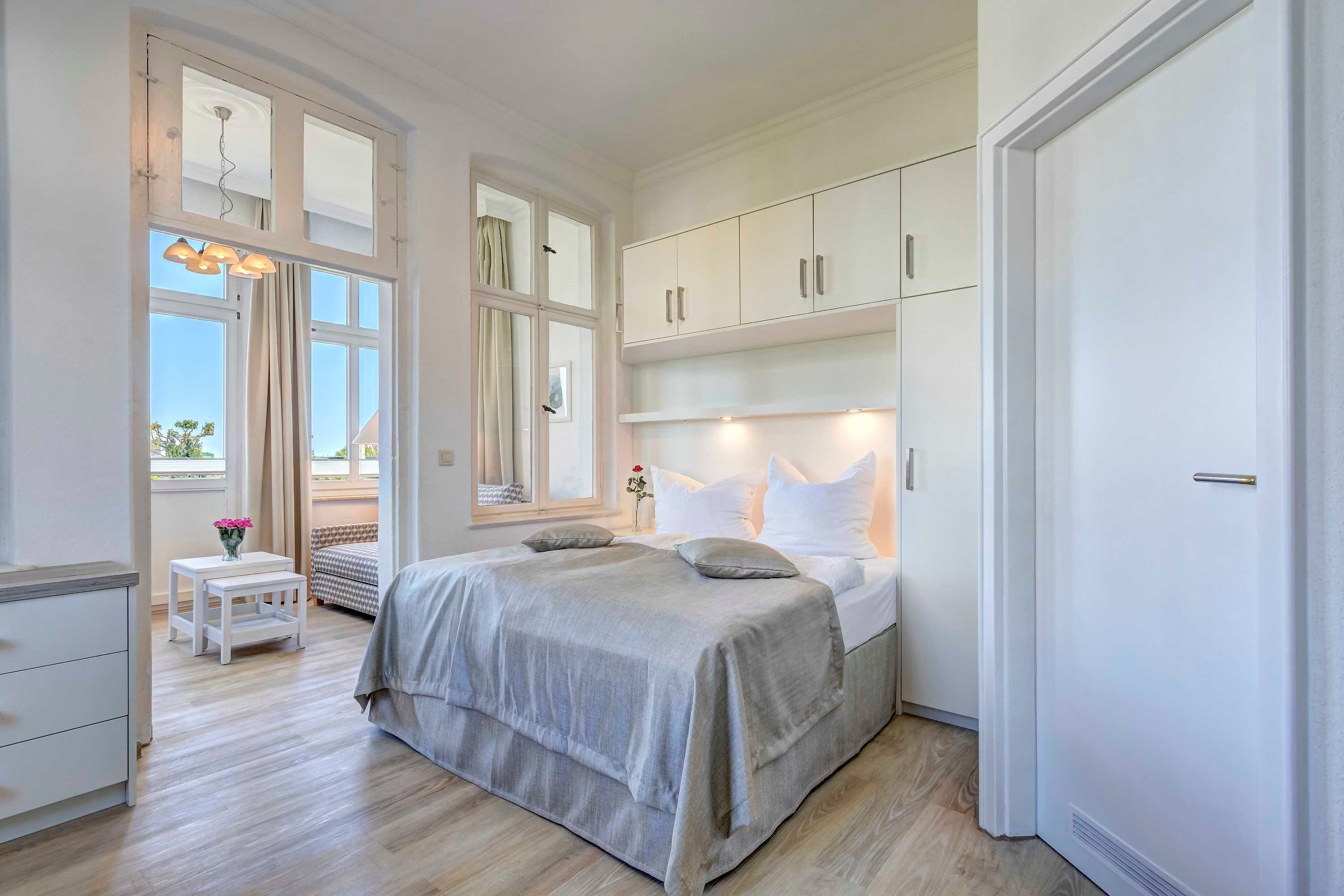 Ein Schlafzimmer mit Bett, Nachttischen, einem Kleiderschrank und einem Fenster mit Vorhängen.