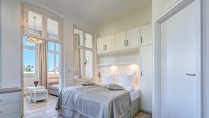 Ein Schlafzimmer mit Bett, Nachttischen, einem Kleiderschrank und einem Fenster mit Vorhängen.