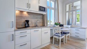 Eine moderne Küche mit weißen Schränken, einer eingebauten Mikrowelle und einem Fenster mit Blick auf Grünflächen.