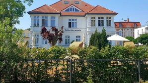 Ein großes, zweistöckiges Gebäude mit rotem Ziegeldach und zahlreichen Fenstern. Am Gebäude ist ein Schild mit der Aufschrift 'Villa Germania'.