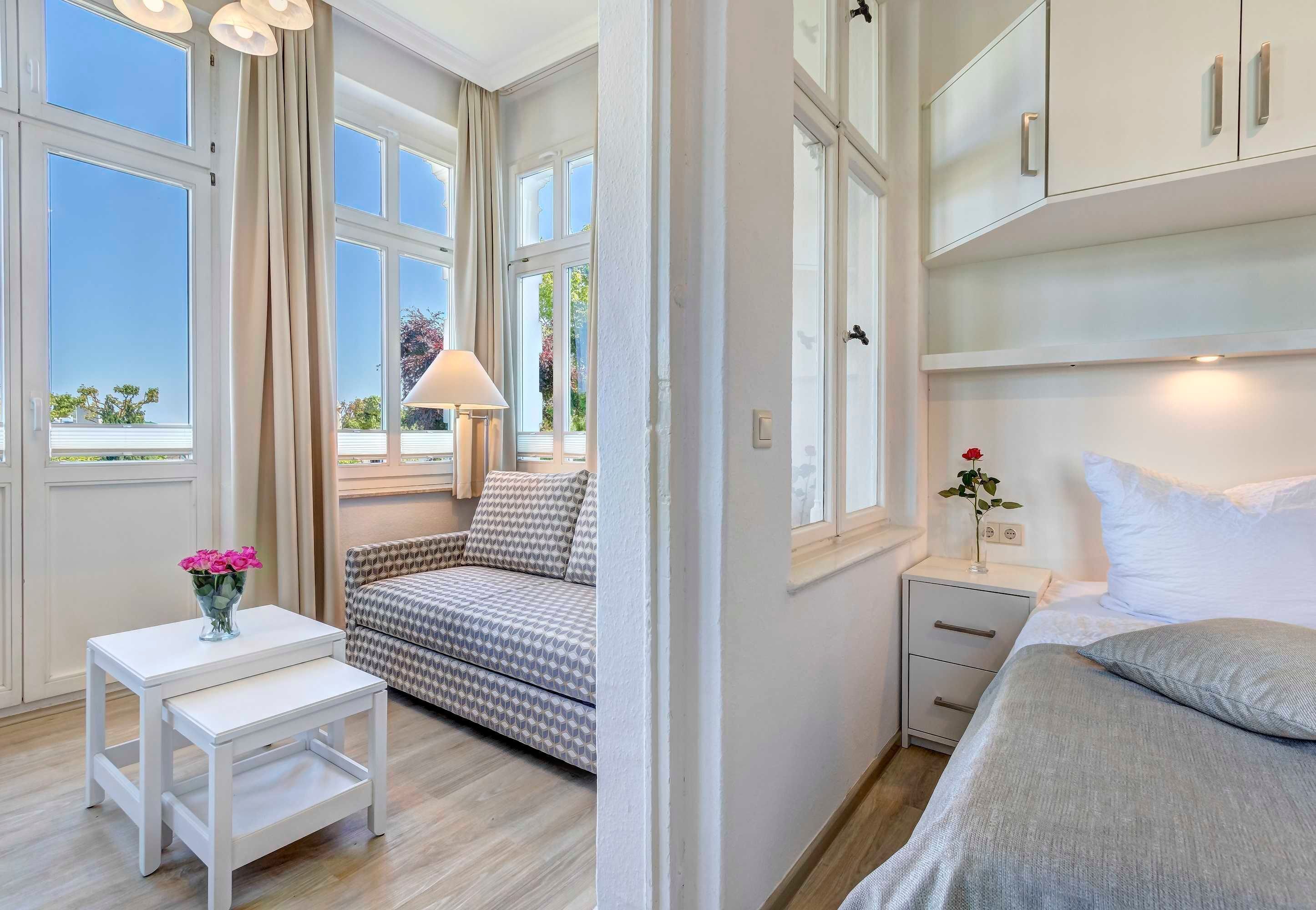 Une chambre à coucher comprenant un lit, une table de chevet, une commode et une fenêtre avec des rideaux.