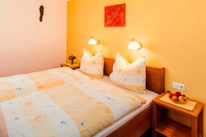 Habitació d'hotel amb un llit, dues taules de nit amb làmpades i un ram de flors, i un plat de fruita sobre la taula de nit.