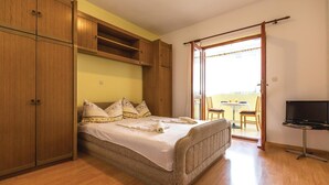 A bedroom with a bed, wooden wardrobe, and a TV. - Amazing apartment in Makarska with house sea view (Makarska)