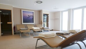 Zona de spa con sillones reclinables, toallas y un amplio ventanal.