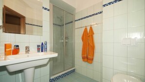 Un baño con lavamanos, espejo, ducha e inodoro.