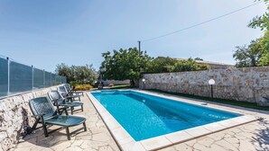 A rectangular swimming pool with a stone border, surrounded by a stone wall and a metal fence. - Lovely home in Rosolini SR with private swimming pool, can be inside or outside (Rosolini SR)