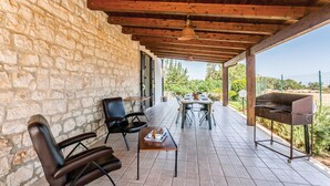 A covered patio with stone walls, a wooden ceiling, and a view of greenery. - Lovely home in Rosolini SR with private swimming pool, can be inside or outside (Rosolini SR)