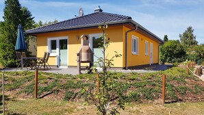 En gul bygning med tegltag, en klokke og et lille haveområde.
