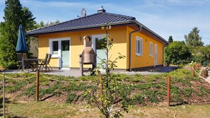 A yellow building with a tiled roof, a bell, and a small garden area.