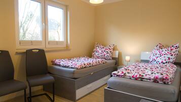 Ein kleines Schlafzimmer mit Bett, Sessel, Nachttisch und Fenster.