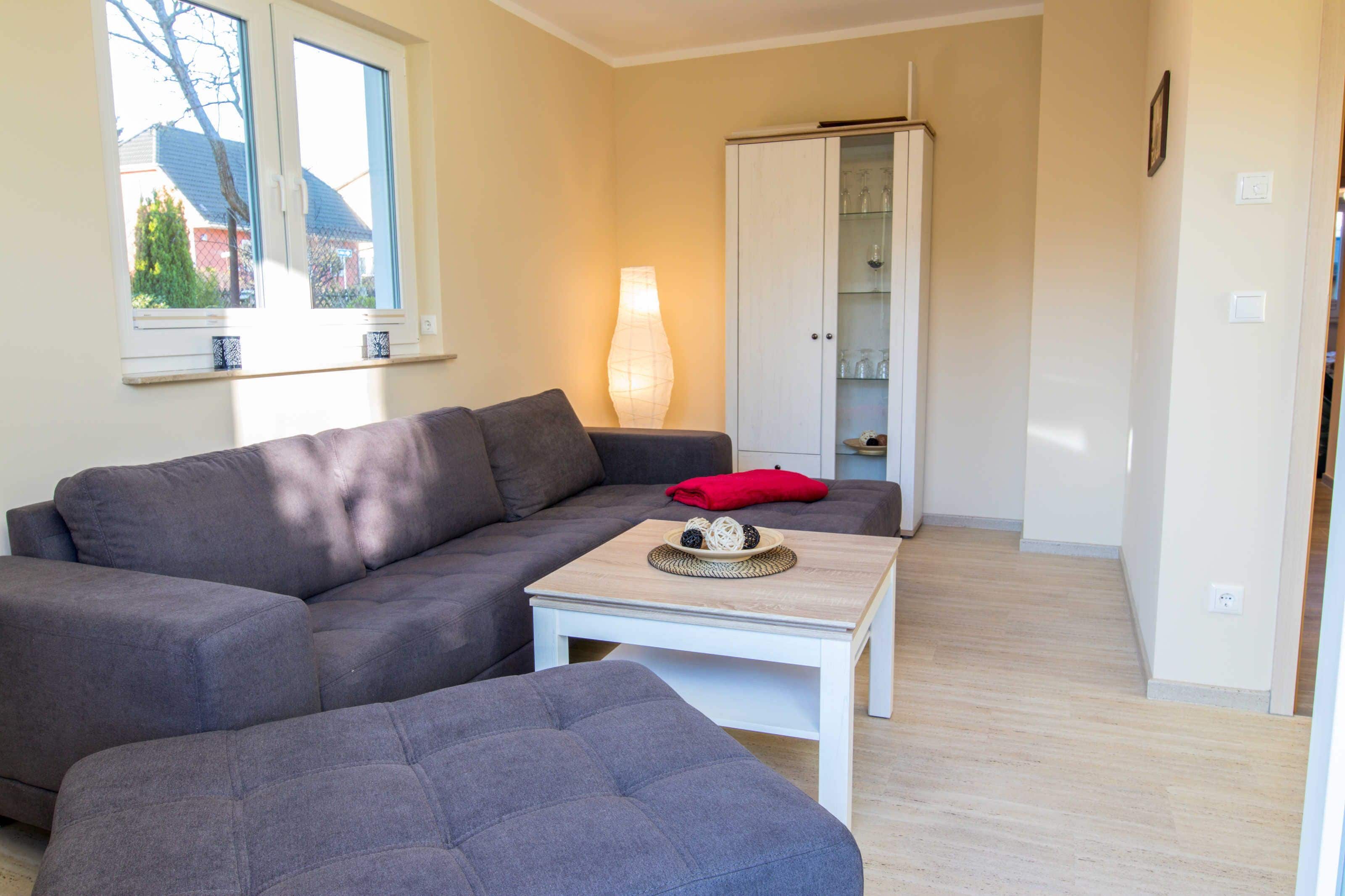 A living room with a grey sofa, a white coffee table, and a cabinet.