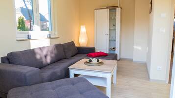 Ein Wohnzimmer mit grauem Sofa, weißem Couchtisch und einem Schrank.