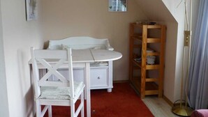 A room with a white desk, a chair, a wooden shelf, and a floor lamp. - Ausacker vacation apartment: small but nice! - Holiday apartment Ausacker (Ausacker)
