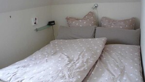 A bedroom with a bed, pillows, and a nightstand. - Ausacker vacation apartment: small but nice! - Holiday apartment Ausacker (Ausacker)