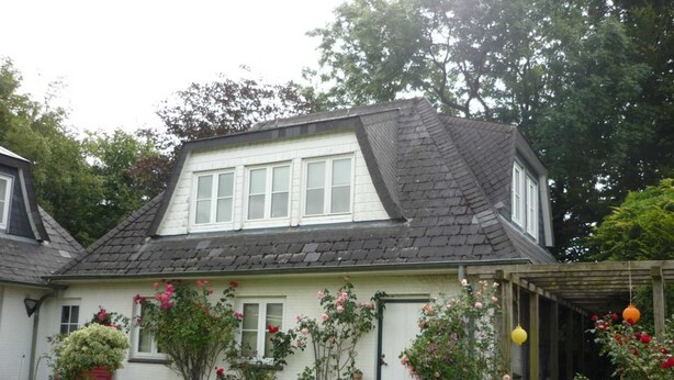 A two-story house with a sloped roof, white exterior walls, and a small porch with hanging lanterns. - Ausacker vacation apartment: small but nice! - Holiday apartment Ausacker (Ausacker)