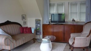 A living room with a sofa, armchair, glass coffee table, and a television on a wooden cabinet. - Ausacker vacation apartment: small but nice! - Holiday apartment Ausacker (Ausacker)