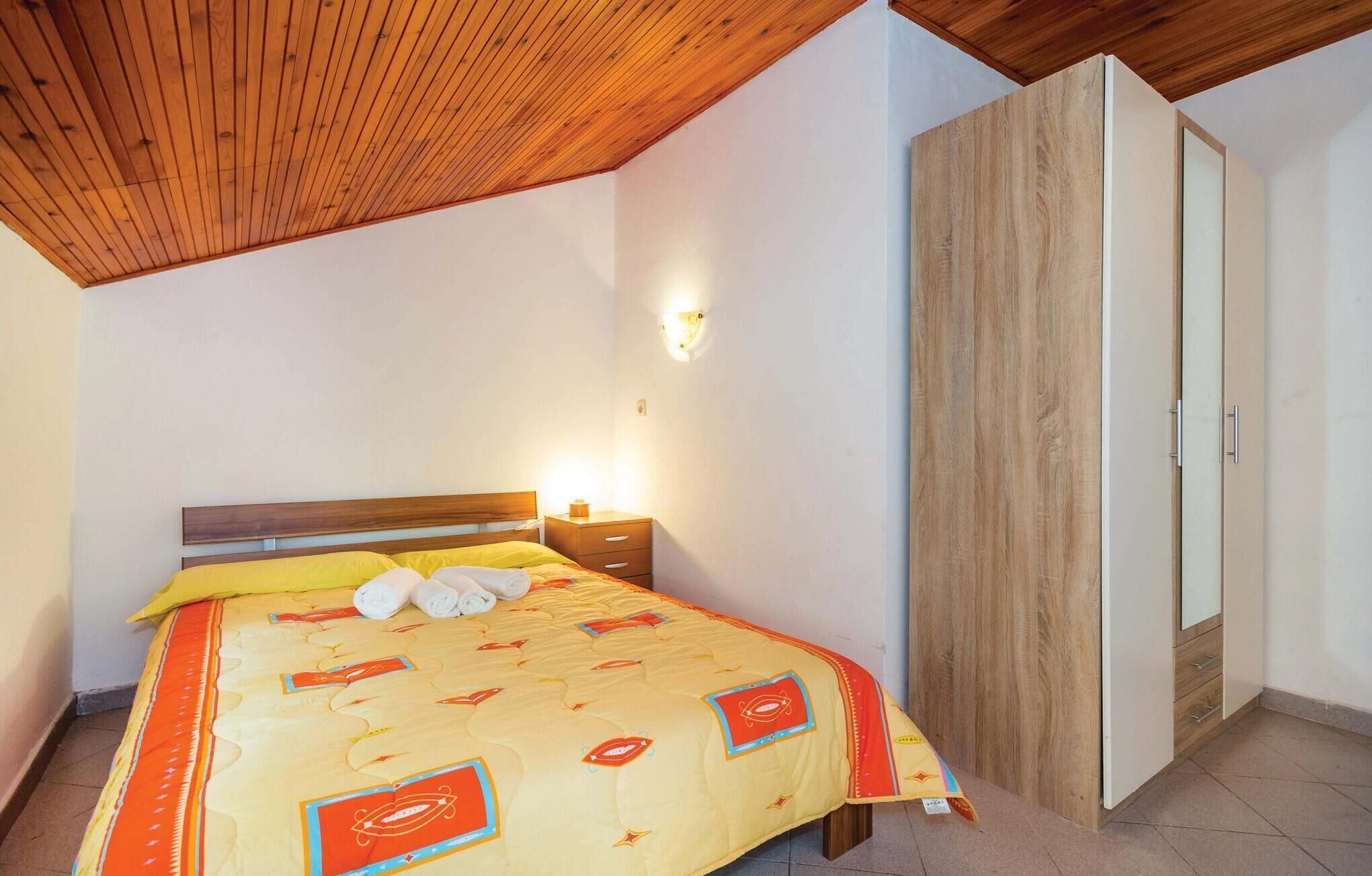 Un dormitorio con cama, cabecera de madera, mesita de noche y armario.