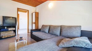 Una sala de estar con un sofá, un televisor y una pequeña mesa.