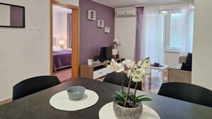 Quarto de hotel moderno com área de refeições, TV e vista para o exterior.