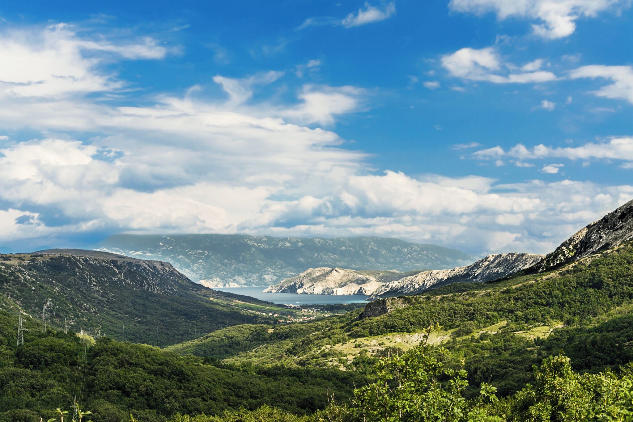 A mountainous landscape with a valley and a body of water in the distance.
