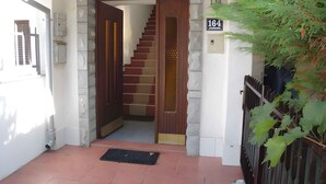 A staircase leading to an upper floor, a number '164' sign, and a metal gate.