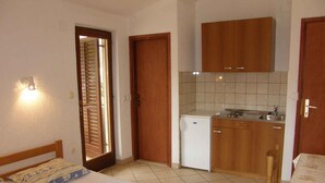 A compact hotel room with two beds, a kitchenette, and a small dining area.