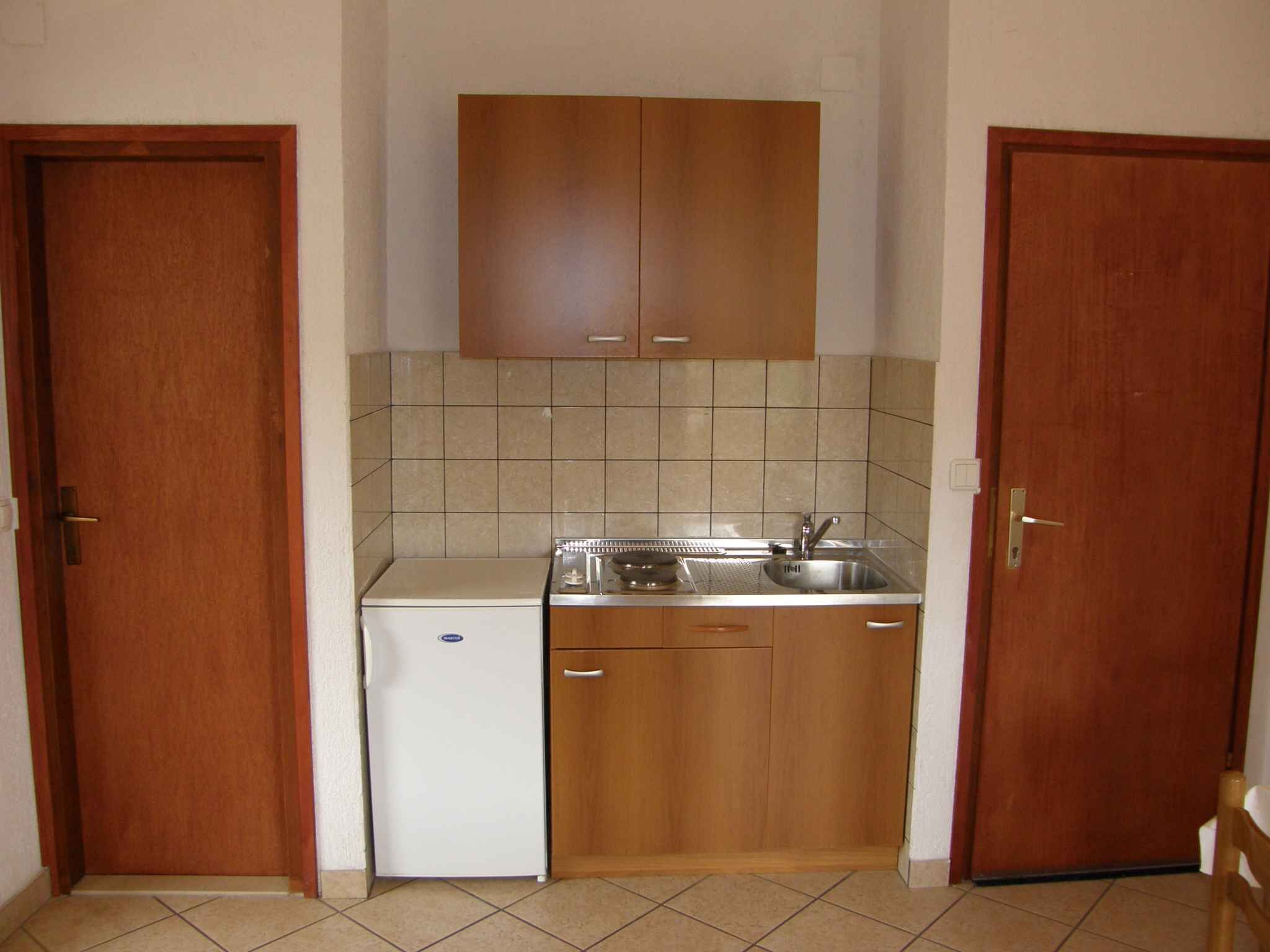 A compact kitchen with wooden cabinets, a white refrigerator, and a sink.