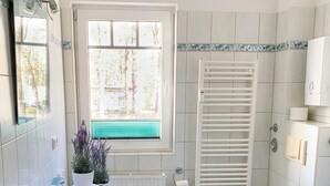 Kylpyhuone, jossa on valkoinen pesuallas, wc ja ikkuna, jossa on sälekaihtimet.