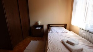 A small, neatly arranged bedroom with a single bed, a nightstand with a lamp, and a radiator. - Holiday apartment with air conditioning (Malinska)
