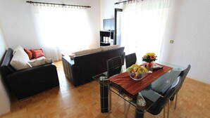 Ein modernes Wohnzimmer mit einem Glastisch, einem schwarzen Ledersofa und einem Flachbildfernseher.