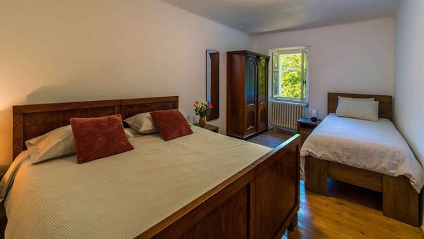 Quarto com duas camas, um guarda-roupa, um radiador e uma janela com vista.