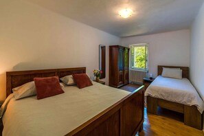 A bedroom with two beds, a wardrobe, a radiator, and a window with a view. - Holiday Apartment in the Countryside (Kožljak)
