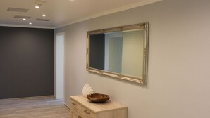 A room with a wooden cabinet, a mirror, and a recessed ceiling light. - Densee: Ferienwohnung Süderende - Apartment (Insel Hiddensee)