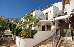 A white two-story building with a balcony, a small garden, and a metal railing. - Awesome home in Montejaque with WiFi (Montejaque)