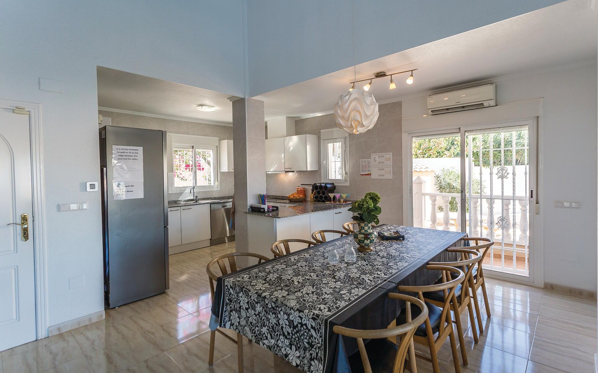 A modern kitchen with white cabinets, a built-in oven, and a dining area with a large table and chairs.