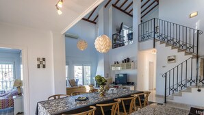 A spacious kitchen with a large island, a dining area with wooden chairs, and a staircase with wrought iron railings. - Amazing home in Ciudad Quesada-Rojales (Ciudad Quesada-Rojales)