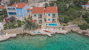 Una propiedad costera con piscina, muros de piedra y agua turquesa cristalina.