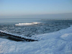 Une étendue d’eau gelée, parsemée de plaques de glace, dont les rives sont recouvertes de neige.