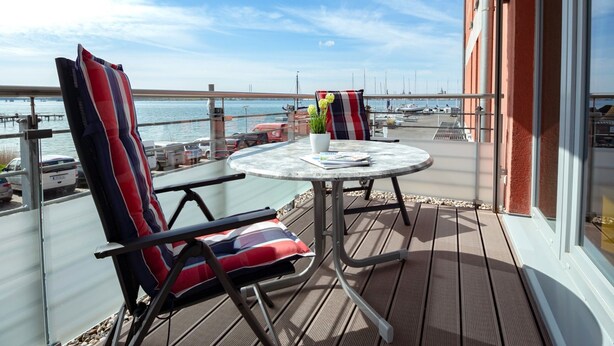 Ein Balkon mit zwei Stühlen, einem Tisch und einem Blumentopf.